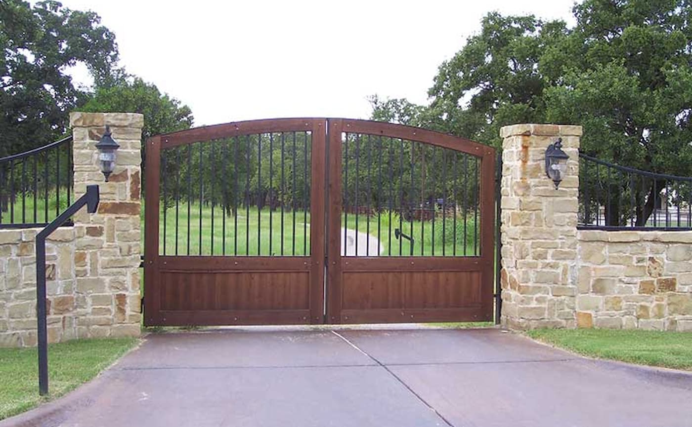 Double panel wood gate closed across paved driveway