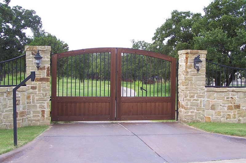 Double panel wood gate closed across paved driveway
